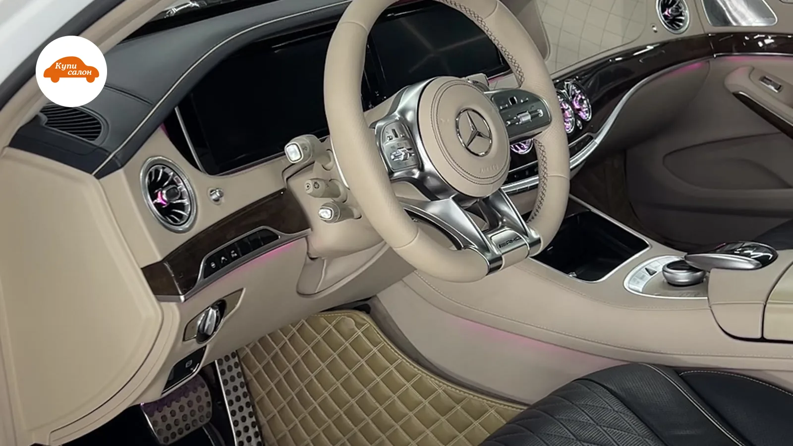 Интерьер Mercedes-Benz S-класса с перетянутым рулем бежевой кожей, черными сиденьями с перфорацией и бежевыми ковриками