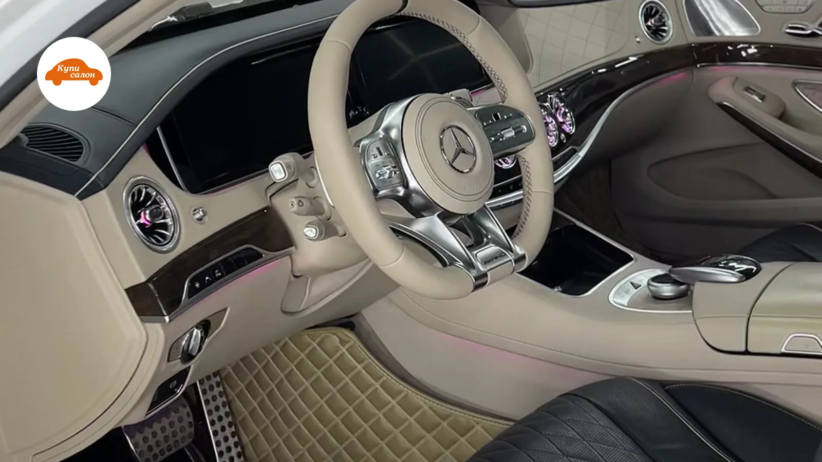 Интерьер Mercedes-Benz с бежевыми ковриками, черными сиденьями и амбиентной подсветкой