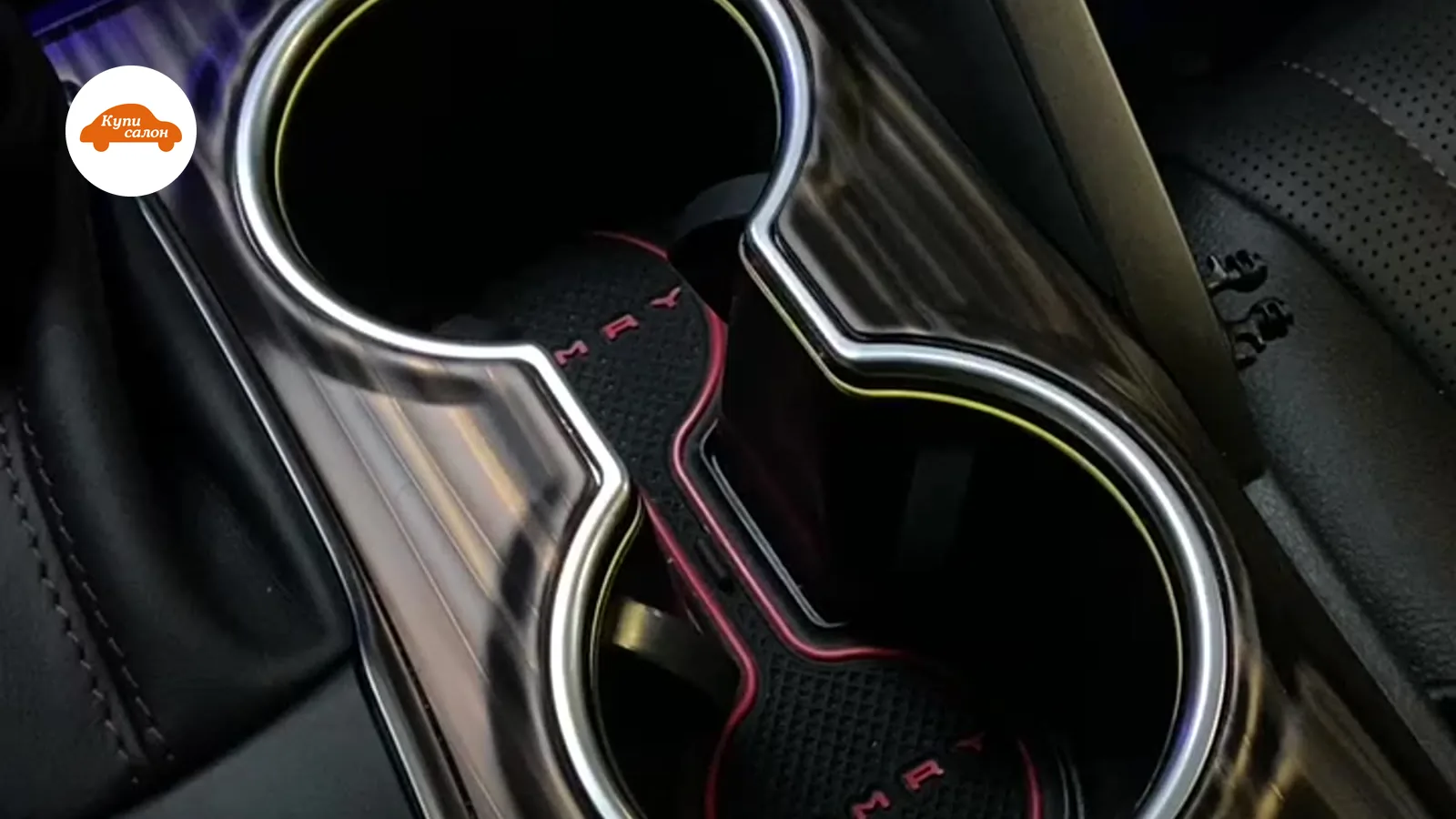 Интерьер Toyota Camry с амбиентной подсветкой и кастомными ковриками в подстаканниках, черный пластик и кожа.
