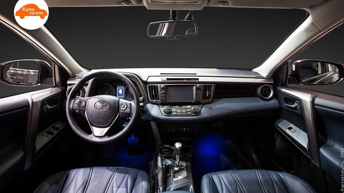 Интерьер Toyota RAV4 с синей амбиентной подсветкой, черными кожаными сиденьями с перфорацией и строчкой
