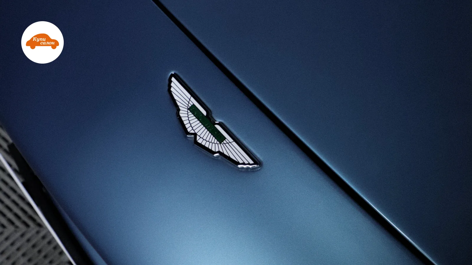 Шильдик Aston Martin на синем кузове автомобиля