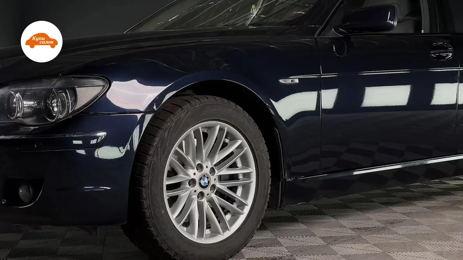 BMW темно-синего цвета, оклеенный защитной пленкой, вид сбоку на переднюю часть и дверь.