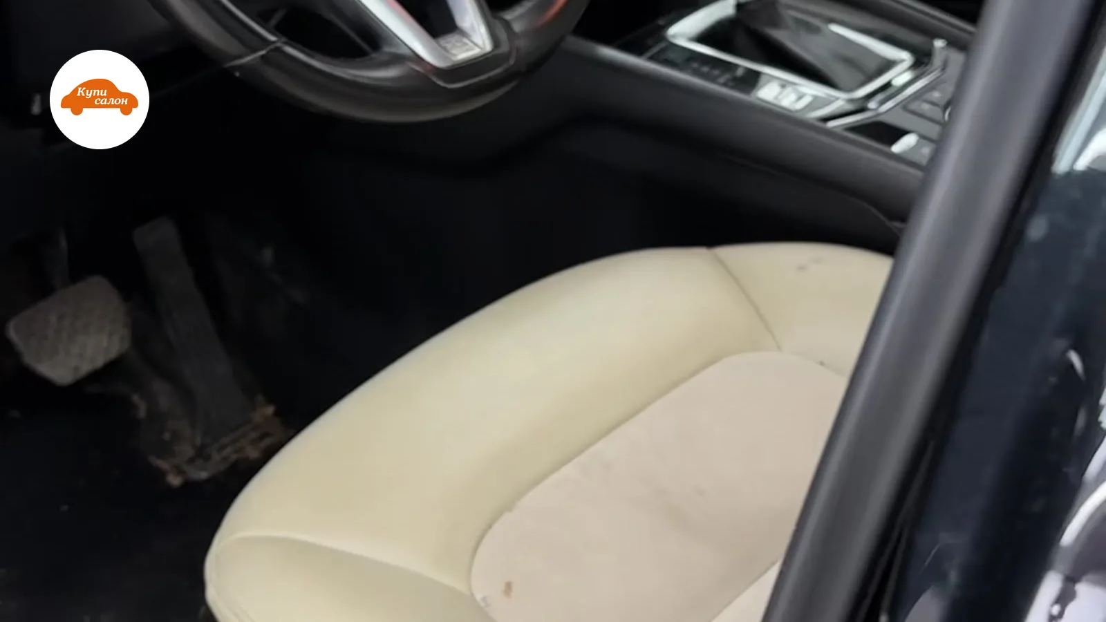 Интерьер автомобиля Mazda, вид на водительское место с бежевыми кожаными сиденьями и черным рулем