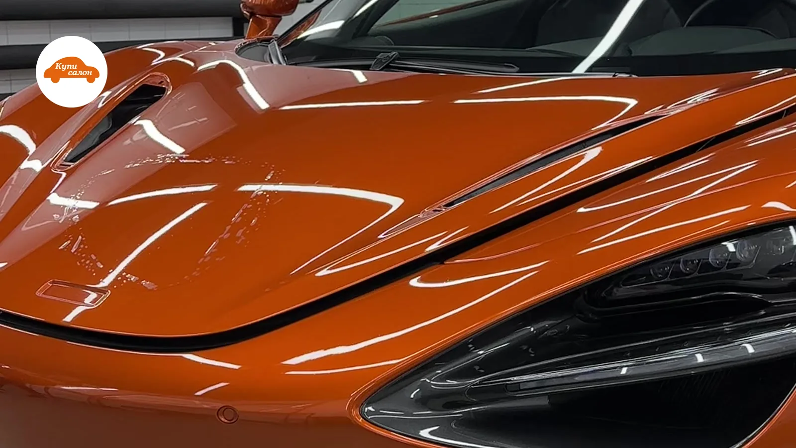 Оранжевый спорткар McLaren, оклеенный полиуретановой пленкой, в детейлинг-студии.