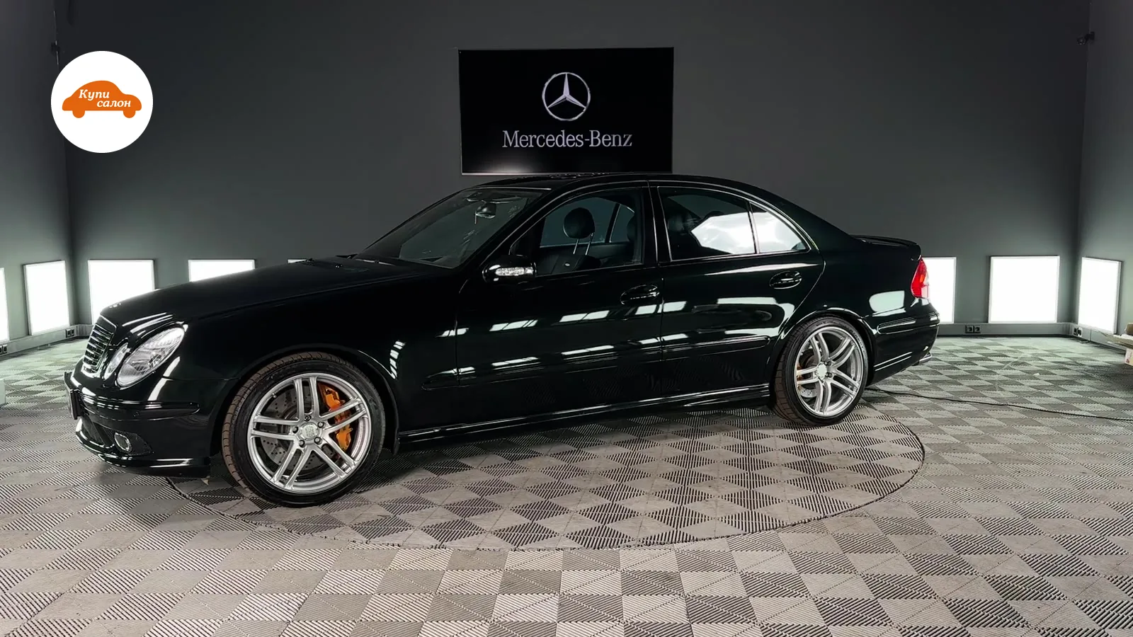 Черный седан Mercedes-Benz, вид сбоку, на поворотной платформе в детейлинг-студии