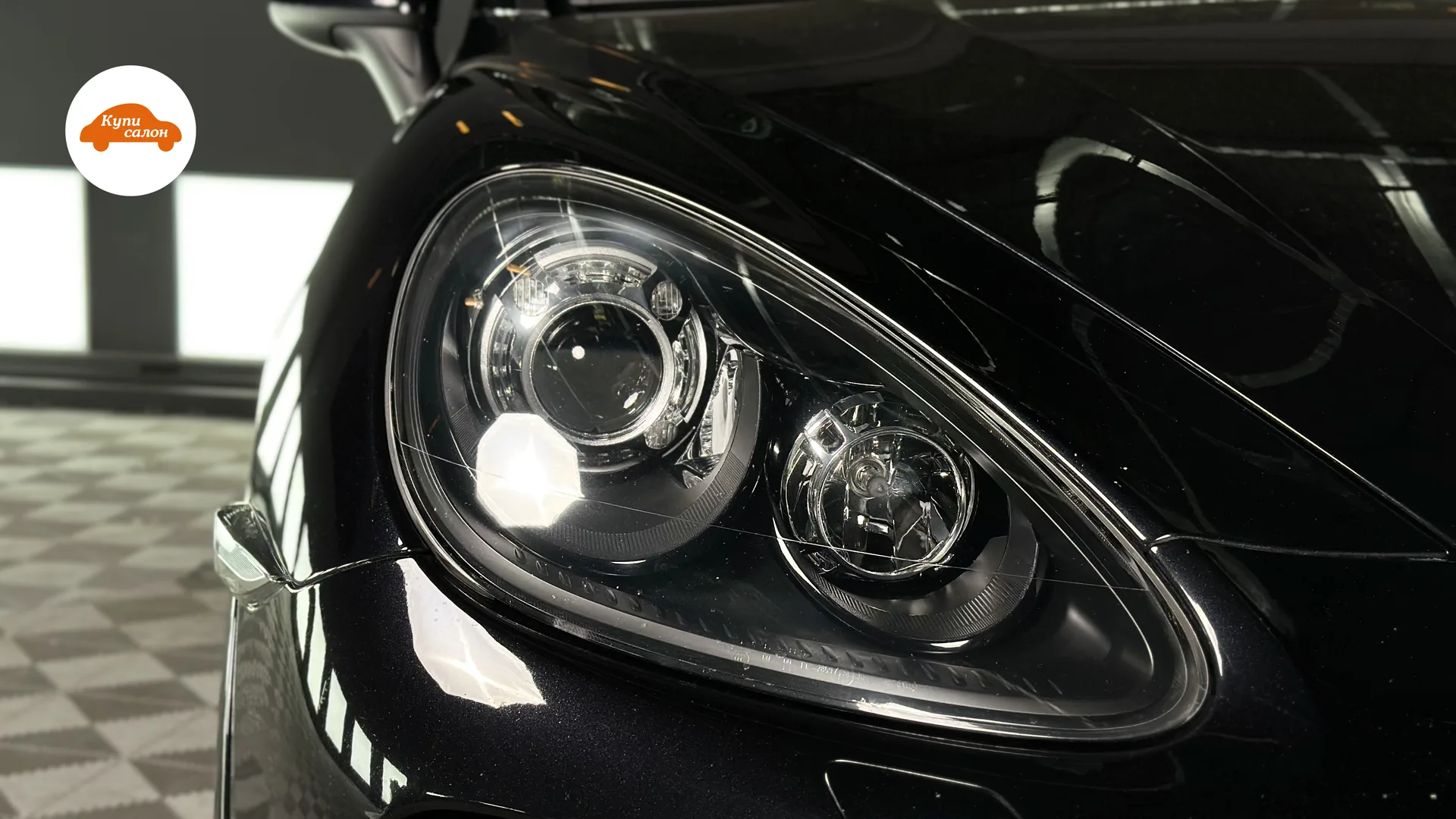 Фара черного автомобиля Porsche Cayenne, покрытая защитной пленкой, после полировки.