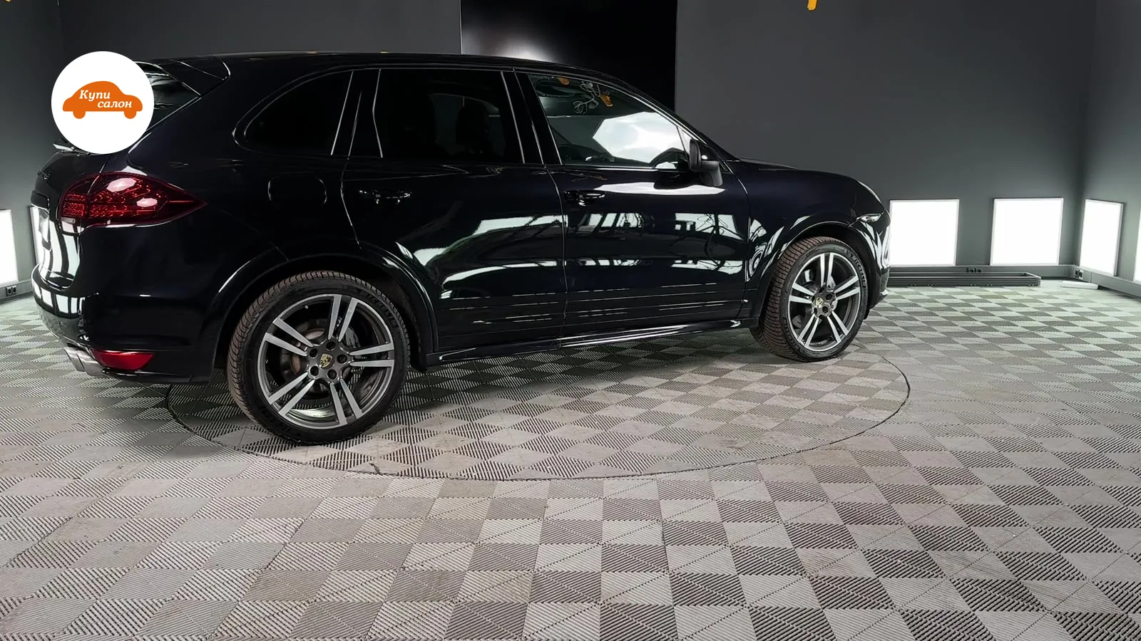 Черный Porsche Cayenne, вид сбоку, на поворотной платформе в детейлинг-студии