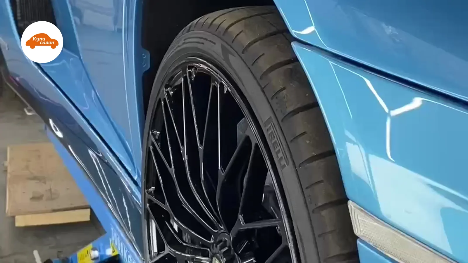 Голубой суперкар Lamborghini на подъемнике, вид сбоку, черные диски, шины Pirelli