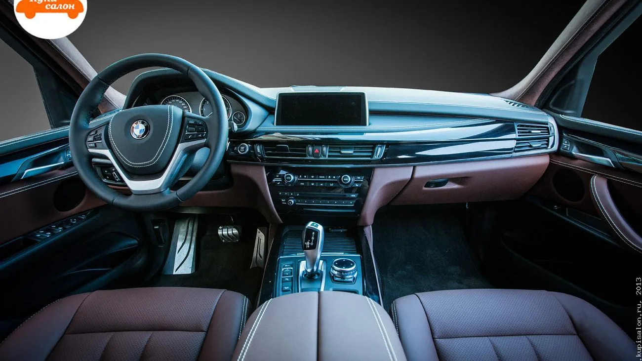 Перетяжка салона BMW: руль, сиденья, центральный подлокотник, консоль и дверные карты в коричневой коже с белой строчкой и перфорацией.