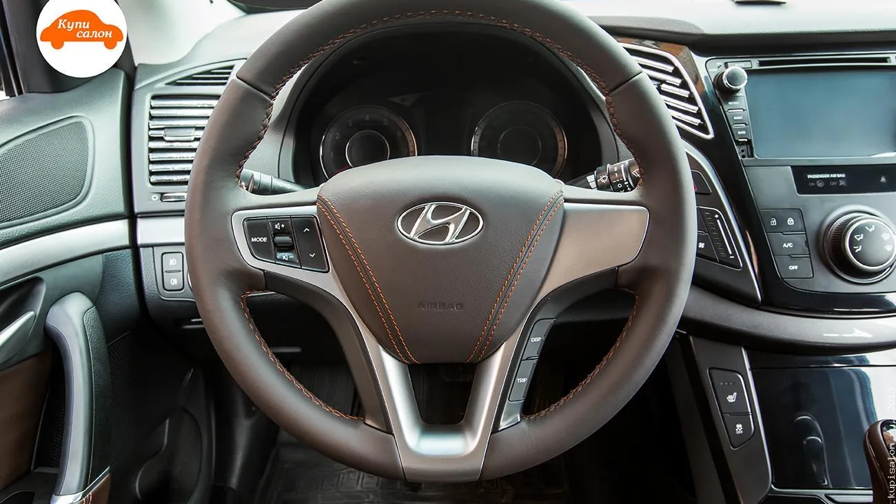 Интерьер Hyundai с перетянутым рулем и дверными ручками коричневой кожей с оранжевой строчкой