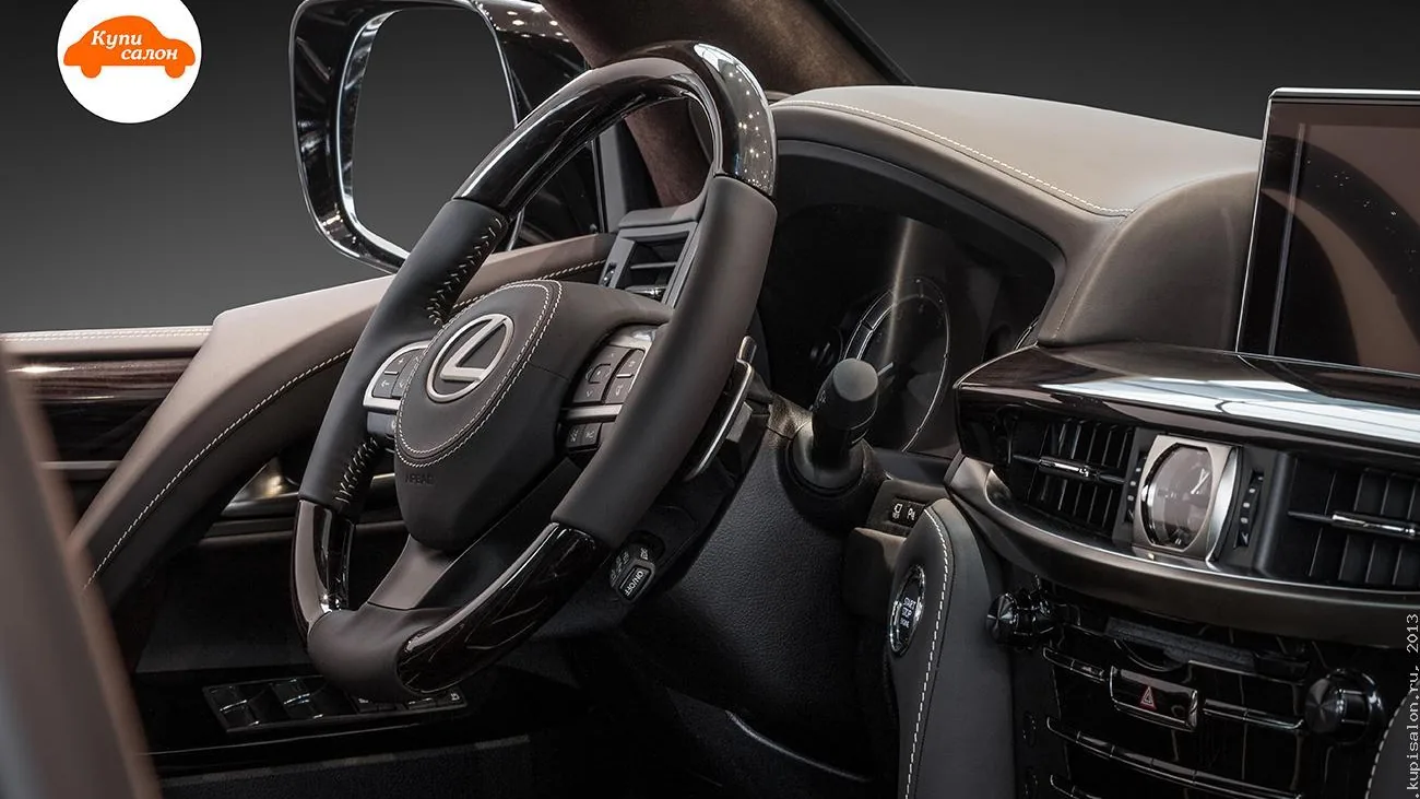Руль Lexus LX 570 сбоку: тёмная кожа со светлой строчкой на ободе, вставки под дерево, подушка руля с круговой строчкой — фото КупиСалон