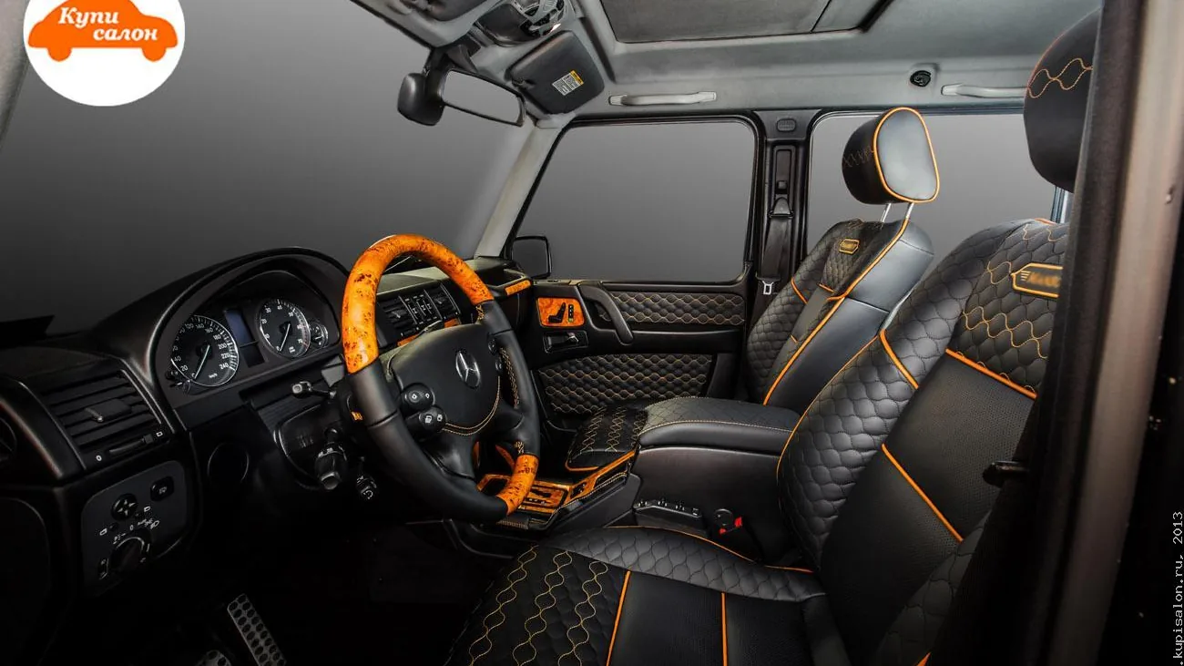 Салон Mercedes-Benz G-класса, перетянутый черной кожей с оранжевой строчкой и деревянными вставками.