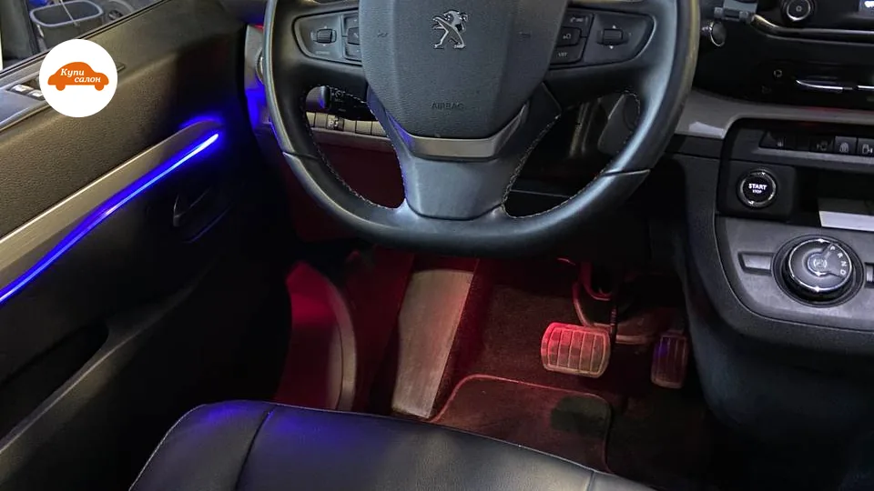 Интерьер Peugeot с перетянутыми черными кожаными сиденьями, синей и красной амбиентной подсветкой.