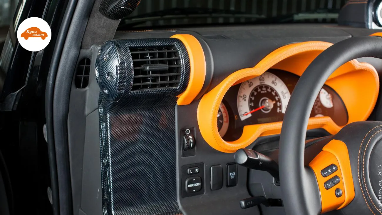 Интерьер Toyota FJ Cruiser с перетяжкой руля, оранжевыми акцентами и карбоновыми вставками.