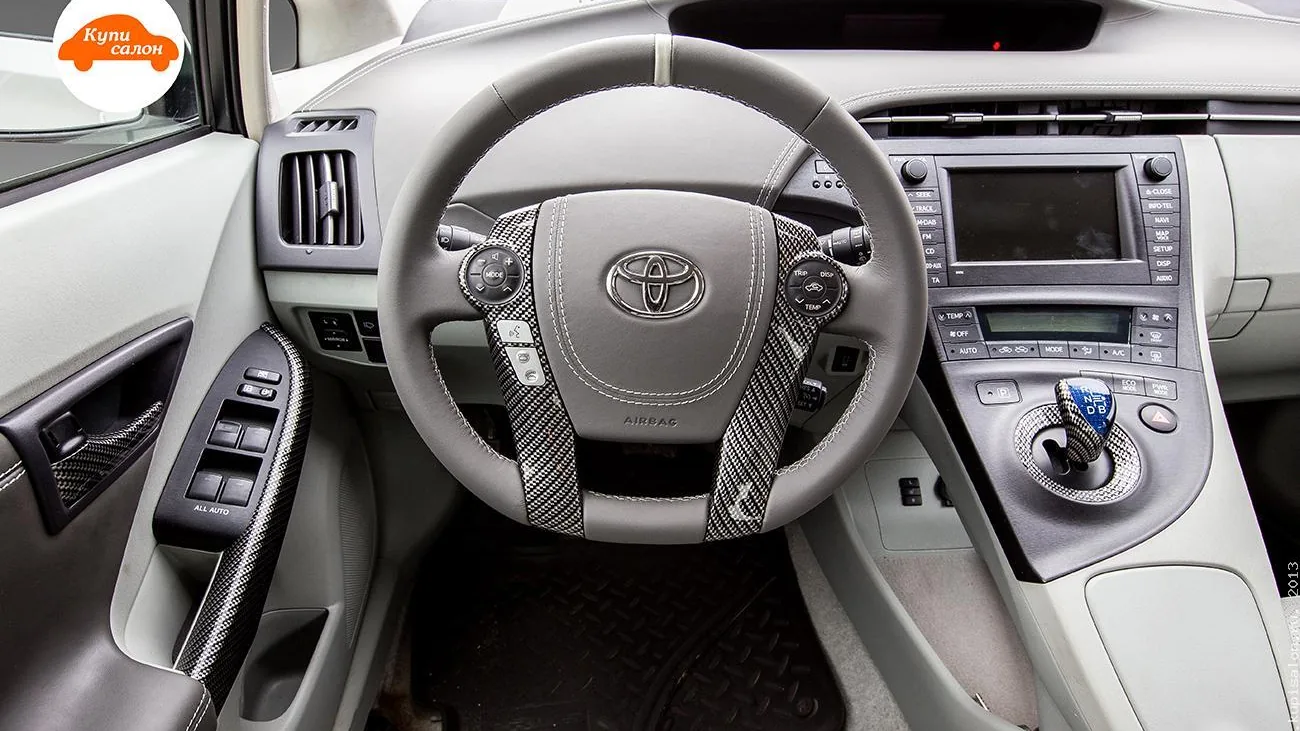 Интерьер Toyota Prius с перетянутым рулем серой кожей, белой строчкой и карбоновыми вставками