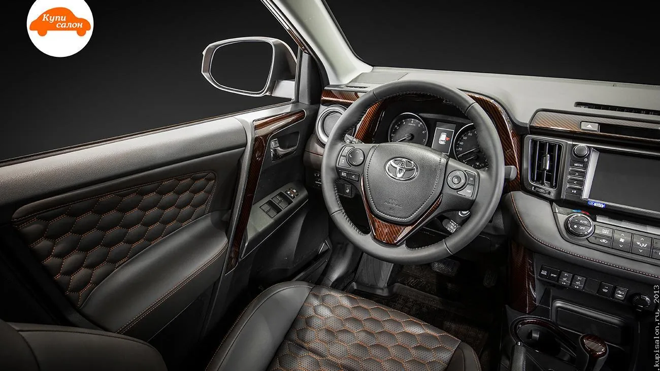 Интерьер Toyota RAV4 с перетяжкой сидений и дверных карт черной кожей с оранжевой строчкой и перфорацией соты, а также вставками под карбон