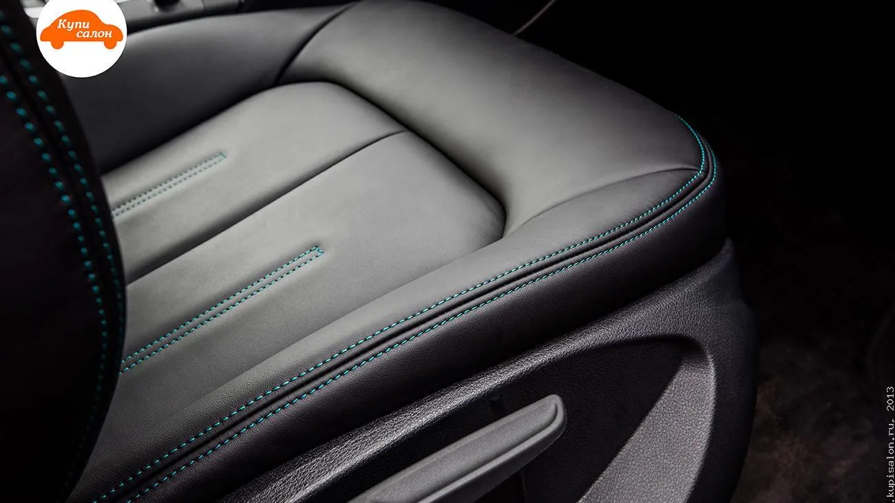 Подушка сиденья Audi A3 крупным планом: чёрная обивка с бирюзовой строчкой, сбоку рычаг регулировки