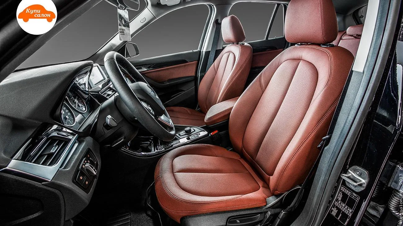 Интерьер BMW с перетяжкой сидений, центрального подлокотника и вставок в двери коричневой кожей, руль перетянут черной перфорированной кожей.