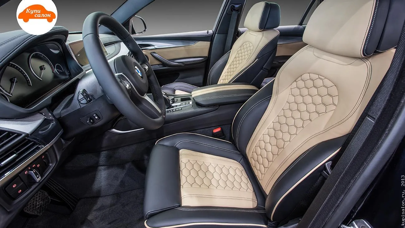 Перетяжка салона BMW: сиденья, подголовники, руль, центральный подлокотник и дверные вставки в черную и бежевую кожу с сотовой перфорацией и белым кантом.