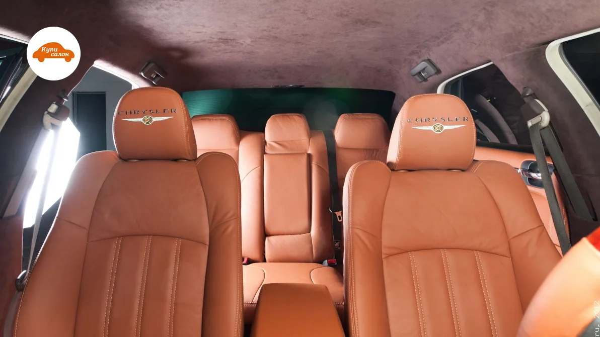 Перетяжка салона Chrysler: сиденья и подлокотник в коричневой коже, потолок и стойки в коричневой алькантаре, вышивка на подголовниках.