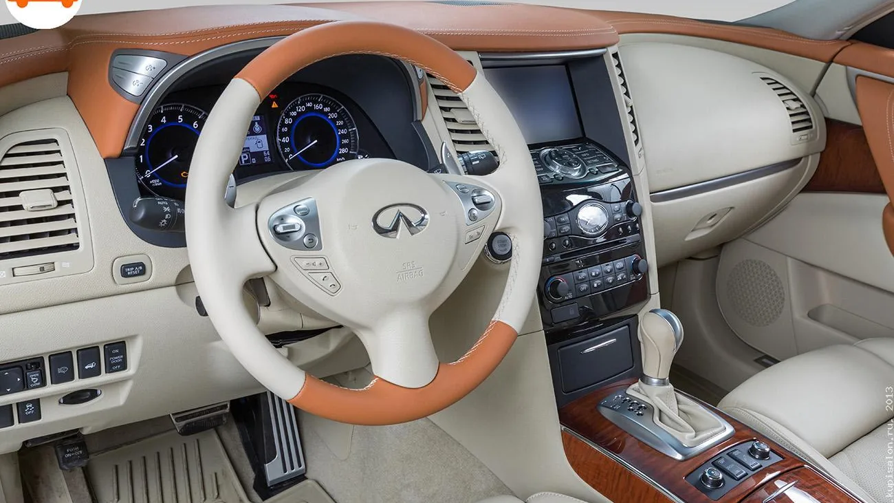 Перетяжка руля, торпедо и центральной консоли Infiniti в бежевую и коричневую кожу с деревянными вставками