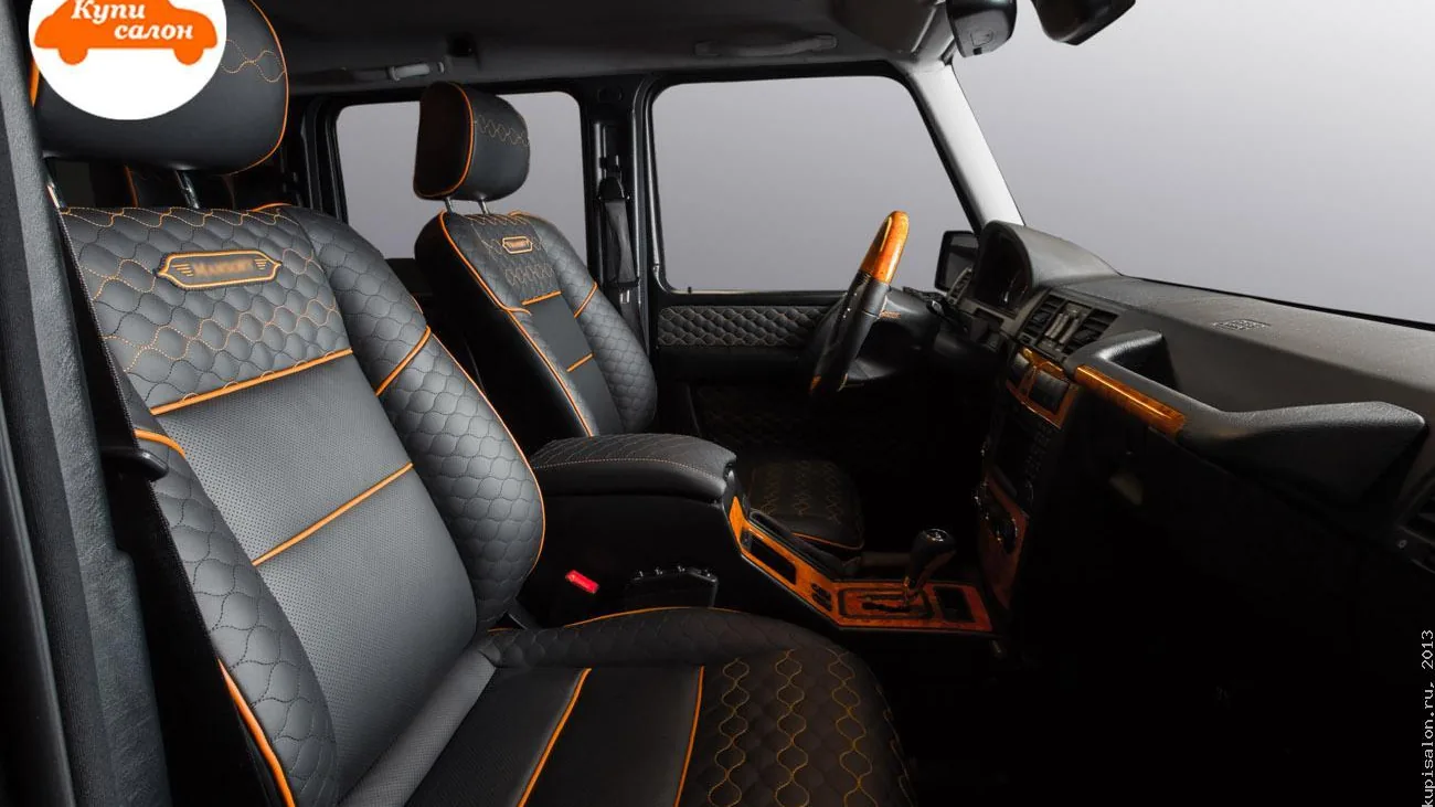 Перетяжка салона Mercedes-Benz G-класса черной кожей с оранжевой строчкой, перфорацией и деревянными вставками.