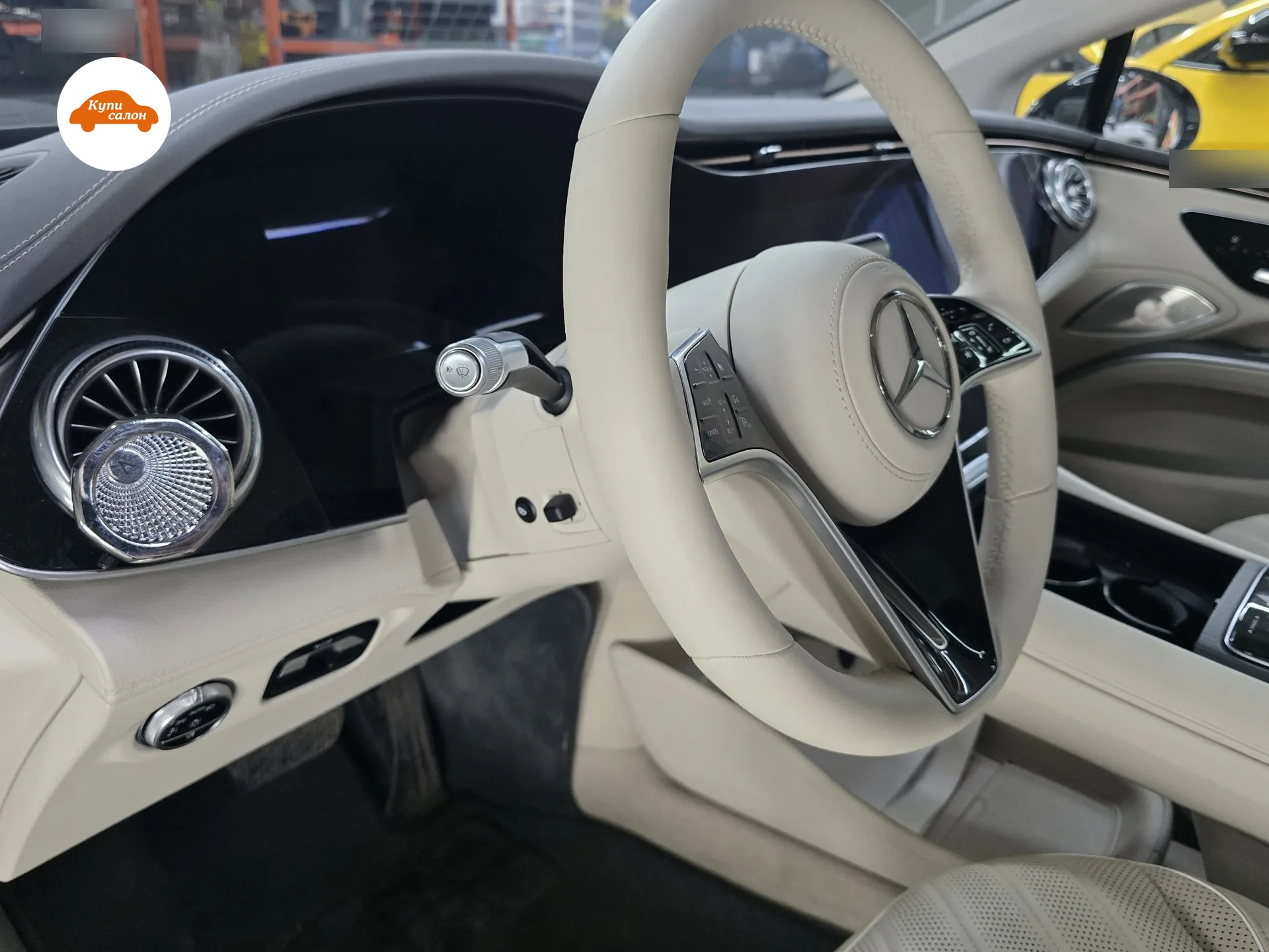 Место водителя Mercedes EQS 580 после работы: руль в светлой натуральной коже наппа, под подрулевым переключателем на кожухе рулевой колонки — кнопка подогрева руля, сиденья в тон