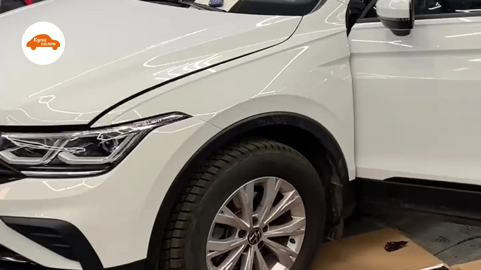 Белый автомобиль Volkswagen Tiguan в процессе оклейки защитной полиуретановой пленкой