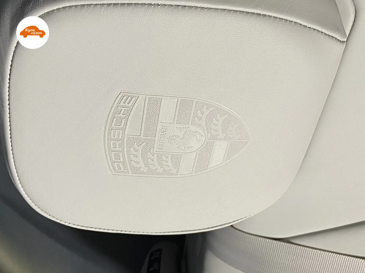 Оттиск герба Porsche на гладком поле подголовника из светлой кожи крупным планом