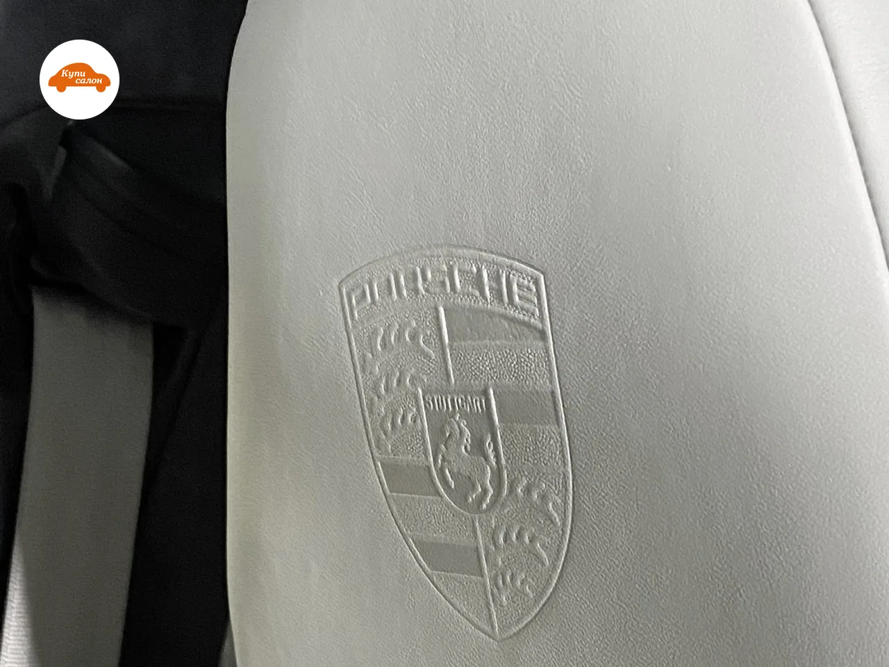 Герб Porsche выдавлен на подголовнике переднего кресла из светло-серой кожи