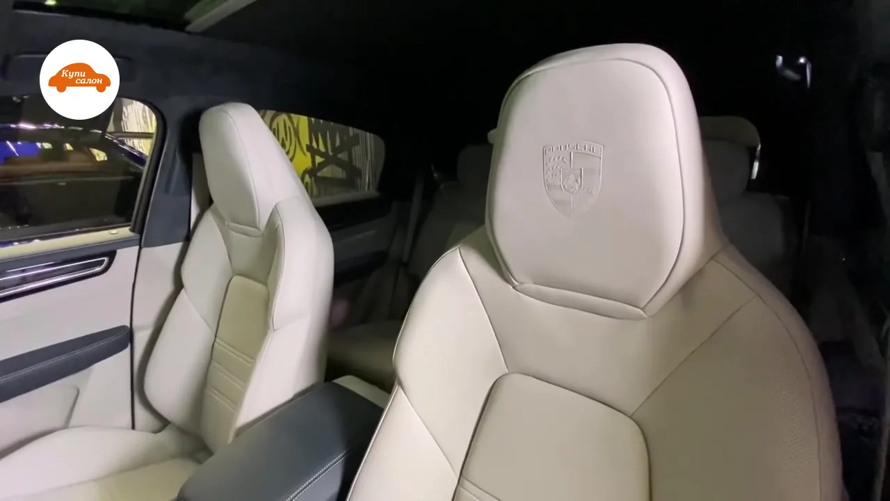 Герб Porsche на подголовнике переднего кресла из светло-серой кожи, вид из салона