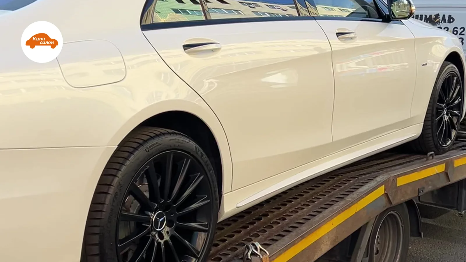 Белый Mercedes-Benz на эвакуаторе, вид сбоку, черные диски.