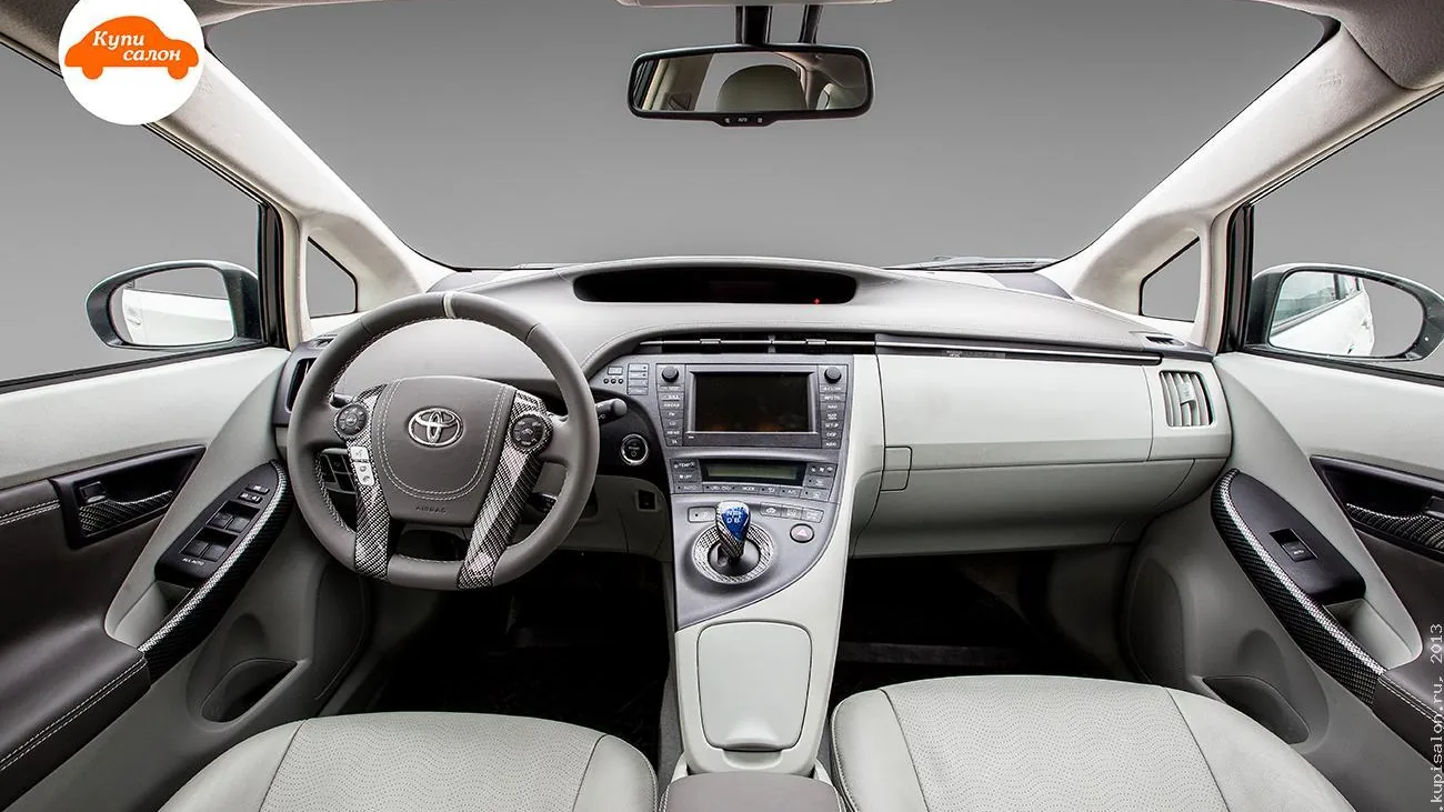 Интерьер Toyota Prius с перетяжкой руля, сидений и дверных вставок в светлых тонах с карбоновыми элементами
