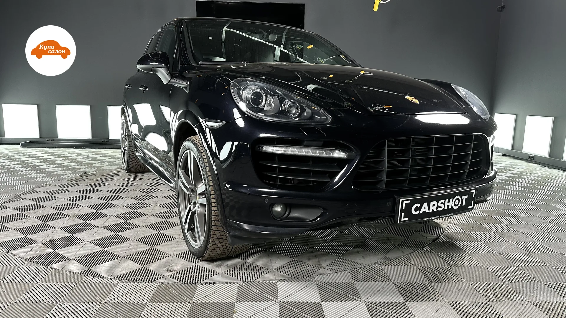 Porsche Cayenne — Чёрный Porsche Cayenne в автоателье, вид спереди-сбоку, серый плиточный пол цеха