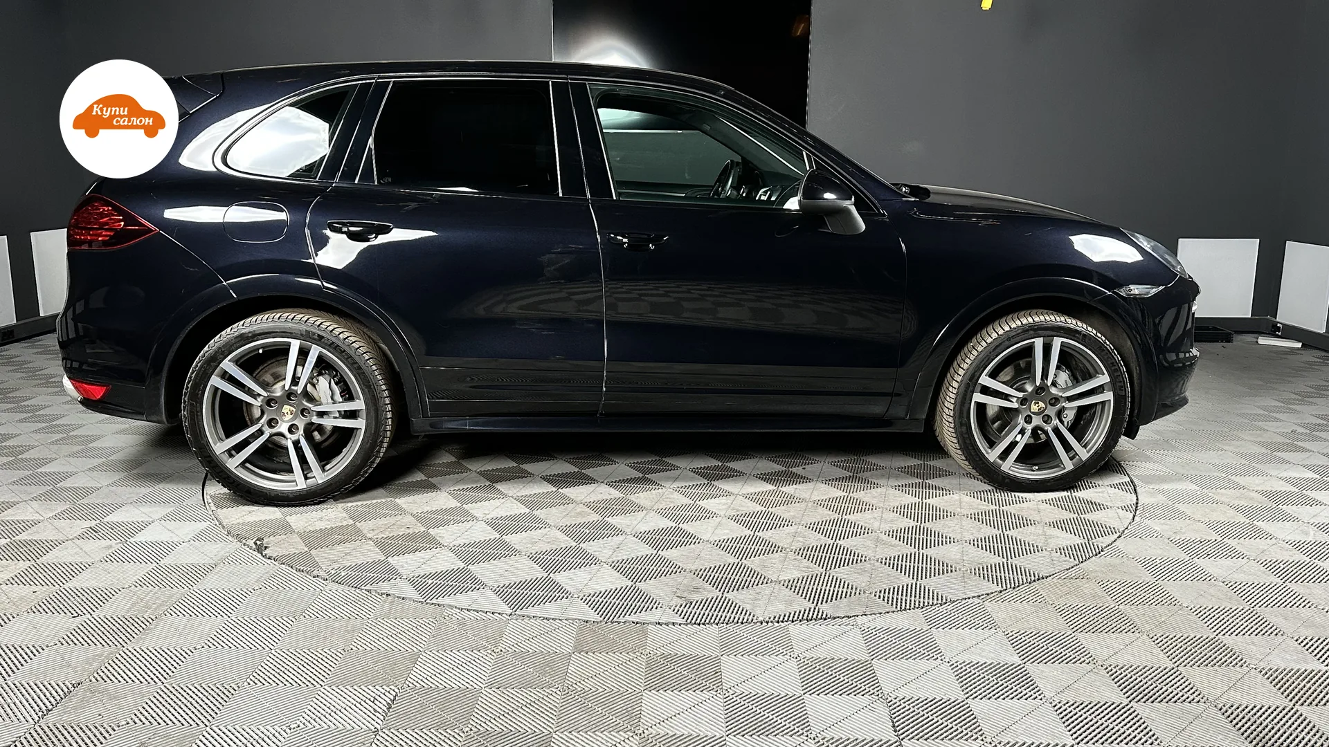 Porsche Cayenne — Тёмно-синий Porsche Cayenne в автоателье, боковой профиль на сером плиточном полу